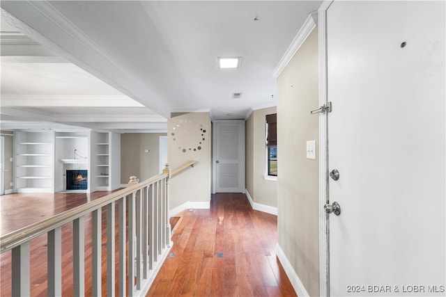 corridor with built in features, wood-type flooring, and ornamental molding