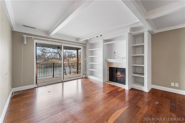 unfurnished living room with beamed ceiling, built in features, and crown molding