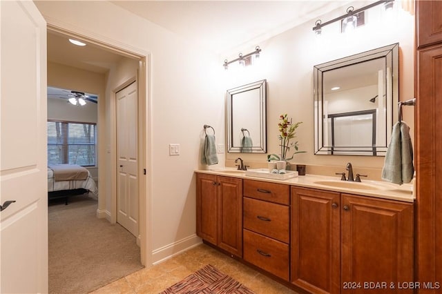 ensuite bathroom with double vanity, a ceiling fan, a sink, and tile patterned floors