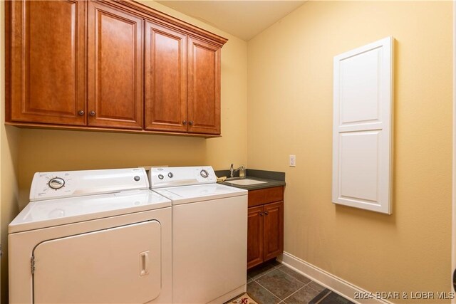 clothes washing area with cabinets, sink, dark tile patterned flooring, and washing machine and clothes dryer