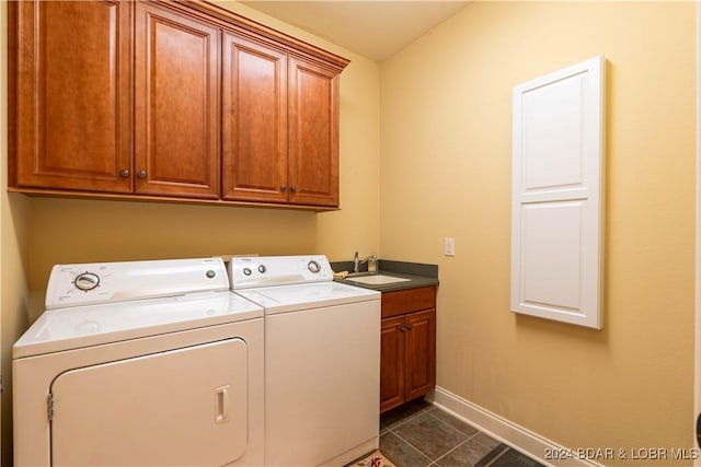 washroom featuring cabinet space, baseboards, dark tile patterned floors, separate washer and dryer, and a sink