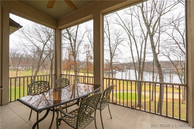 sunroom featuring ceiling fan and a water view