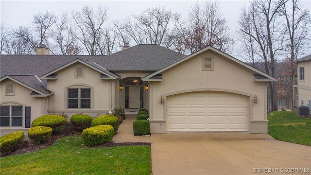 view of front of house with central AC unit, a front yard, and a garage