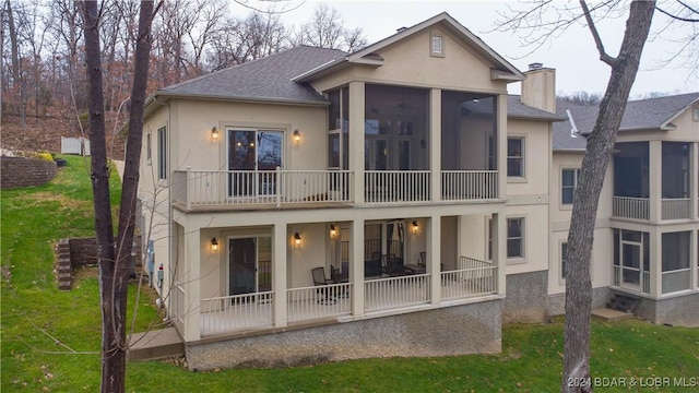 back of house with a lawn, a chimney, a sunroom, and stucco siding