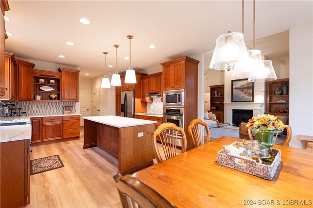 kitchen with light wood-type flooring, backsplash, stainless steel appliances, pendant lighting, and a kitchen island