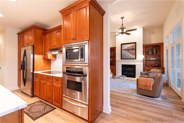 kitchen with appliances with stainless steel finishes, light wood-type flooring, tasteful backsplash, and ceiling fan