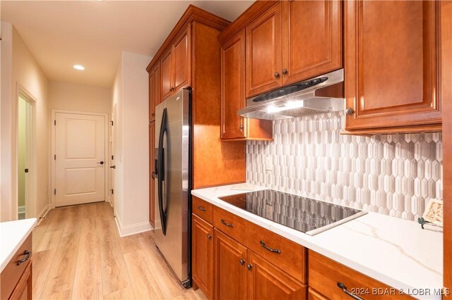 kitchen with black electric stovetop, light hardwood / wood-style floors, stainless steel refrigerator with ice dispenser, and tasteful backsplash