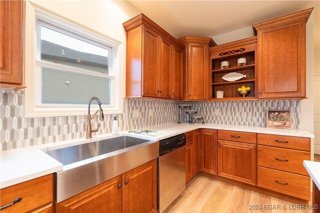 kitchen featuring sink, tasteful backsplash, stainless steel dishwasher, and light hardwood / wood-style flooring