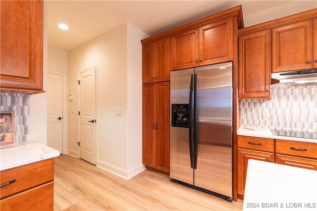 kitchen featuring light hardwood / wood-style flooring, stainless steel fridge with ice dispenser, backsplash, and black electric cooktop