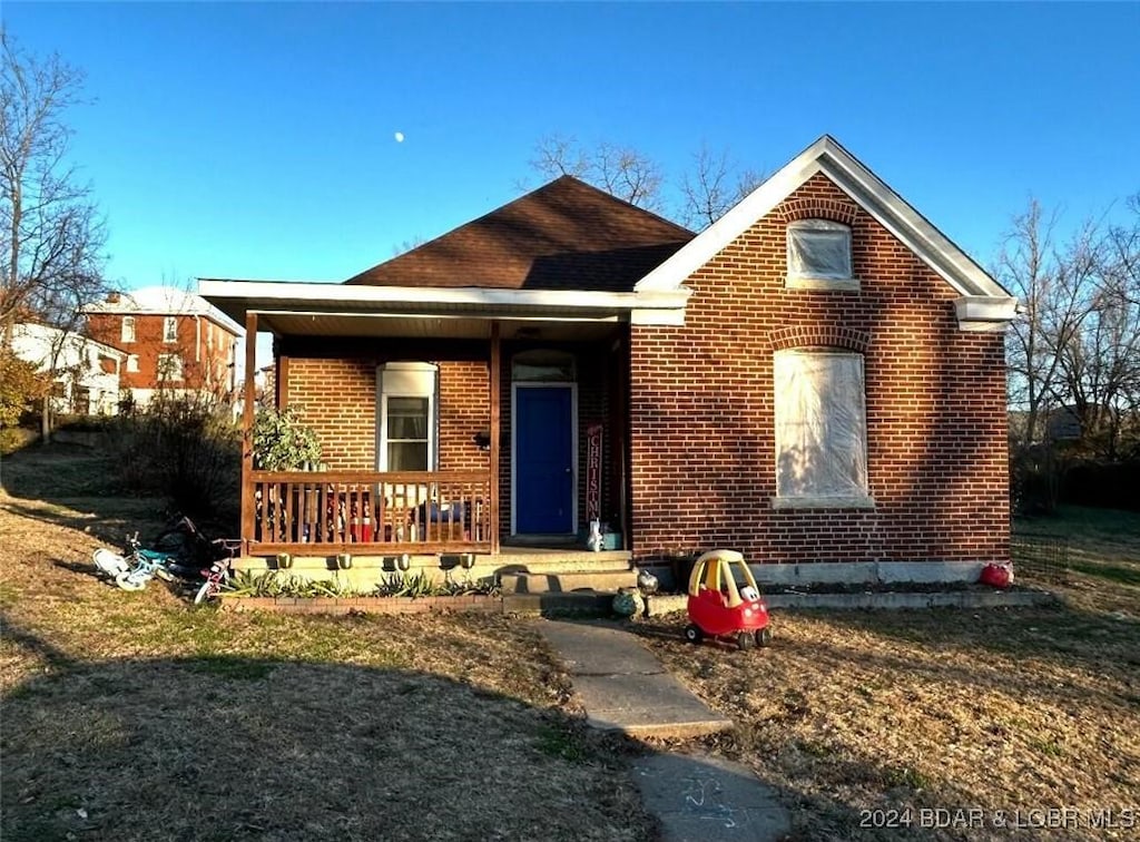 bungalow-style house featuring covered porch and a front yard