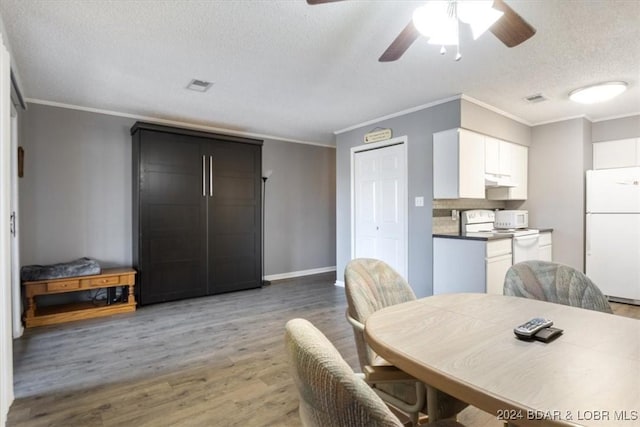 dining space featuring a textured ceiling, hardwood / wood-style flooring, ceiling fan, and ornamental molding