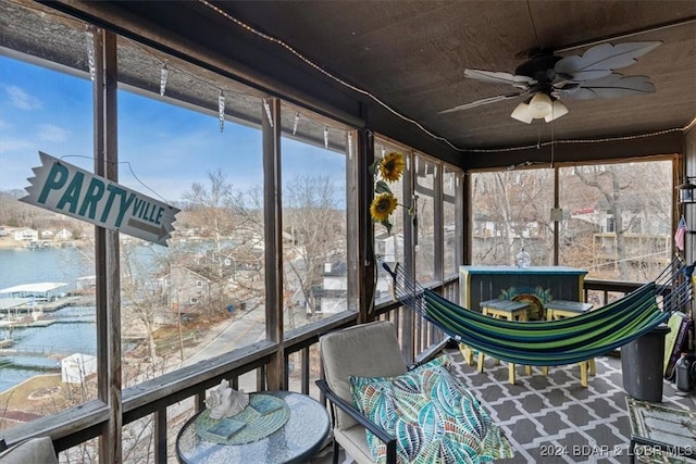 unfurnished sunroom featuring ceiling fan and a water view