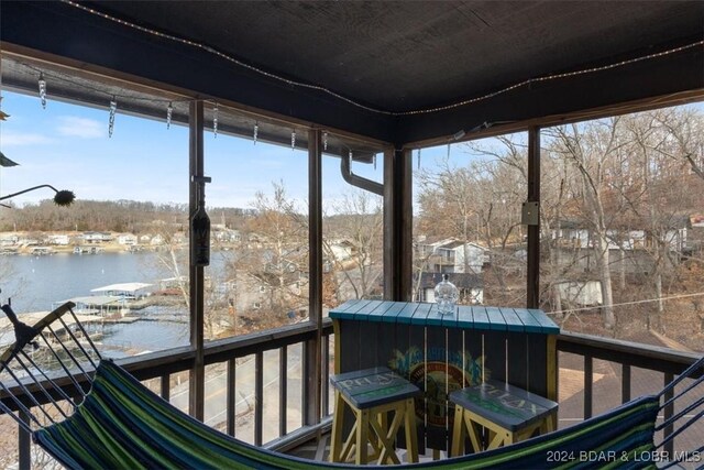 sunroom featuring a water view