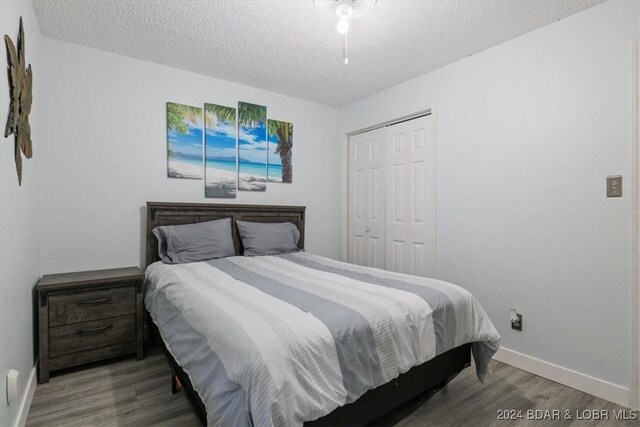 bedroom with a closet, wood-type flooring, and a textured ceiling