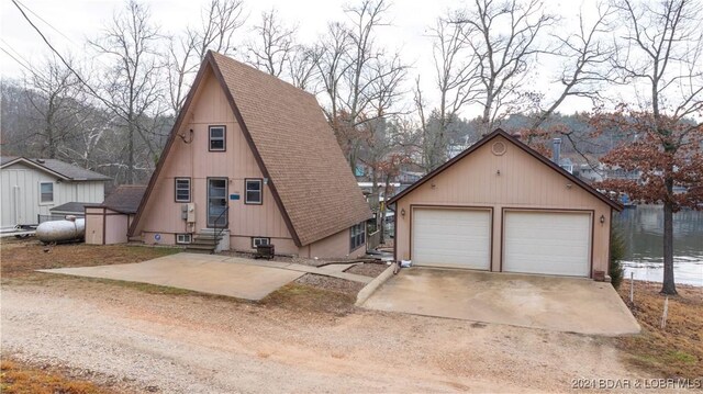 view of front facade featuring an outbuilding, a water view, and a garage