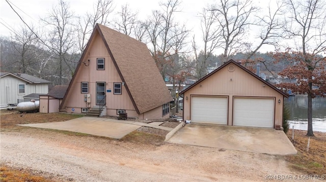 a-frame home with a shingled roof, entry steps, a detached garage, and an outdoor structure