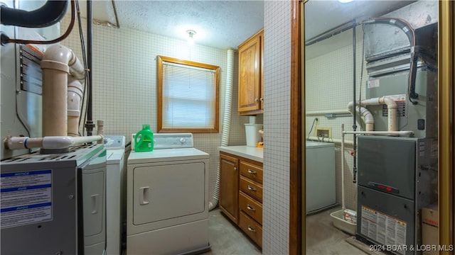 clothes washing area with cabinet space, washer and clothes dryer, and a textured ceiling