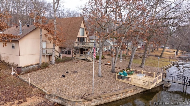 back of house featuring a shingled roof, a water view, and a balcony