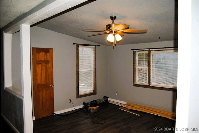 unfurnished room with a textured ceiling, dark hardwood / wood-style floors, vaulted ceiling, and ceiling fan