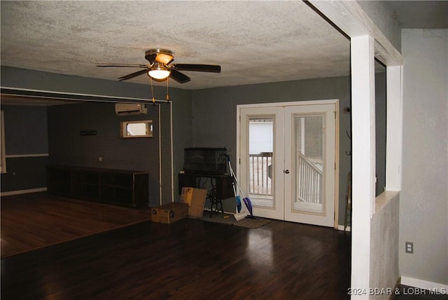 unfurnished living room featuring french doors, a textured ceiling, a wall unit AC, ceiling fan, and wood-type flooring