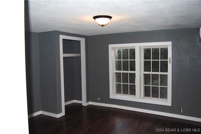 empty room with dark hardwood / wood-style floors and a textured ceiling