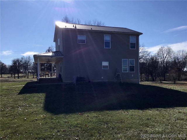 rear view of property featuring a lawn and covered porch