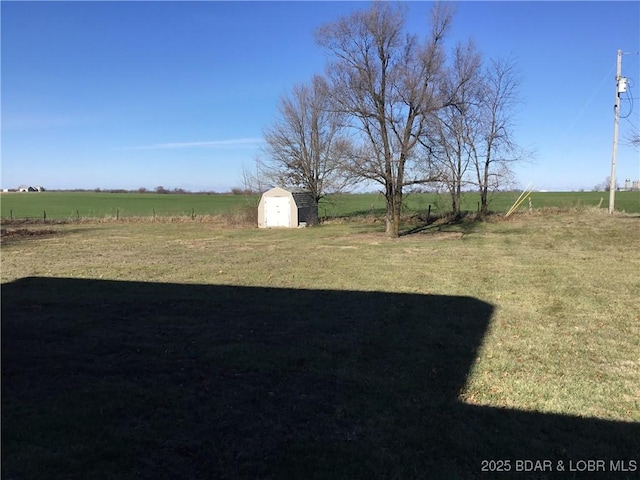 view of yard featuring a rural view and a storage shed