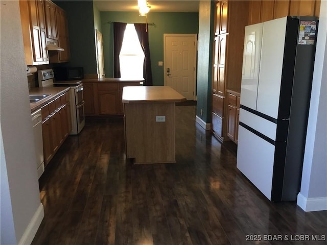 kitchen featuring dark hardwood / wood-style flooring, white appliances, and a kitchen island