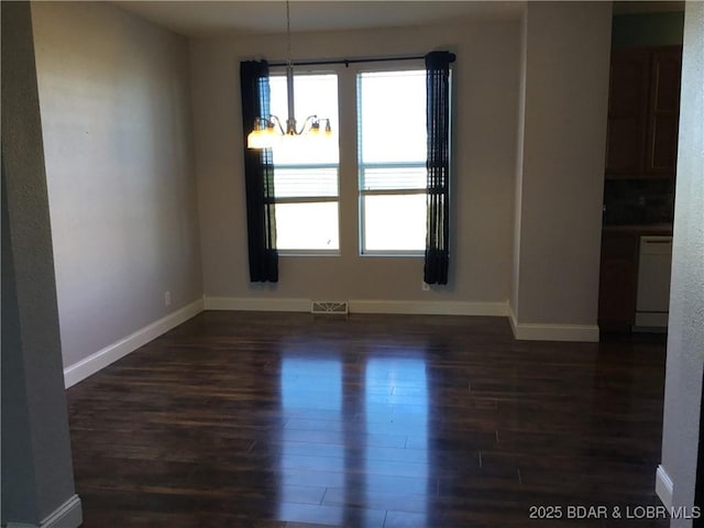 unfurnished room with dark wood-type flooring and an inviting chandelier