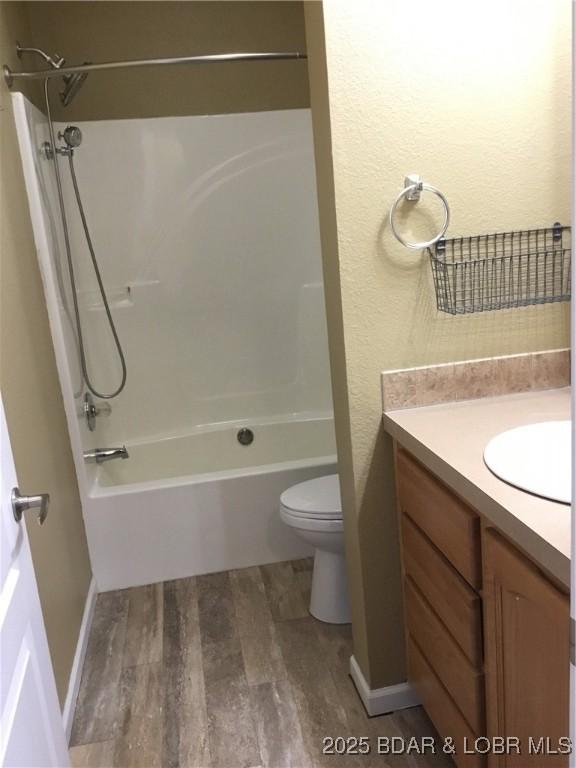 full bathroom with washtub / shower combination, vanity, hardwood / wood-style flooring, and toilet