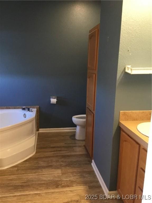 bathroom with hardwood / wood-style floors, vanity, toilet, and a bathing tub