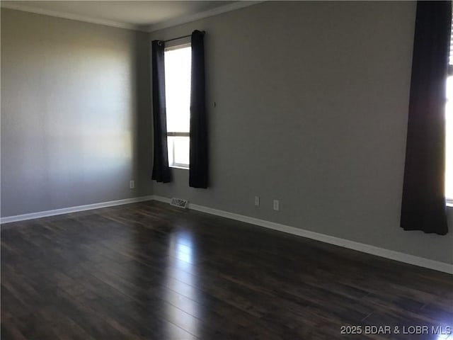 spare room featuring dark wood-type flooring and ornamental molding