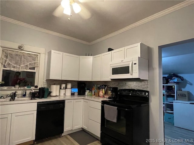 kitchen with white cabinetry, decorative backsplash, ornamental molding, black appliances, and sink