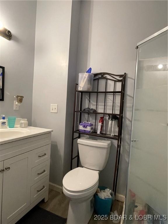 bathroom featuring toilet, a shower with shower door, wood-type flooring, and vanity