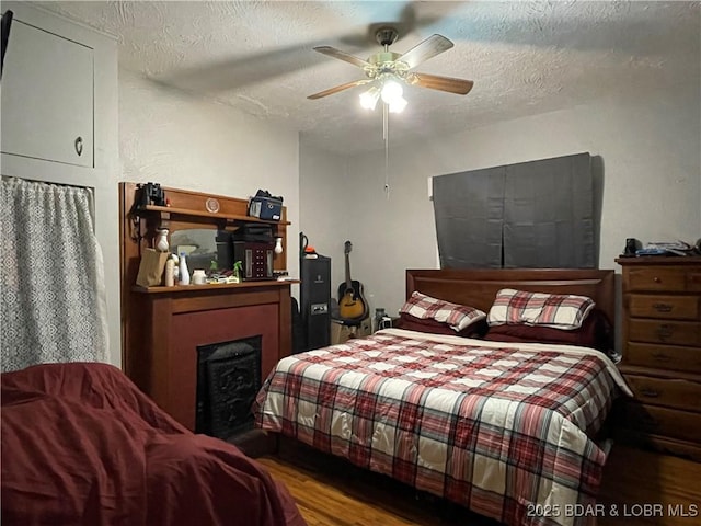 bedroom with a textured ceiling, ceiling fan, and hardwood / wood-style floors