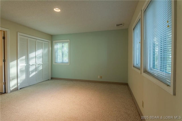 unfurnished bedroom featuring carpet, a textured ceiling, and a closet