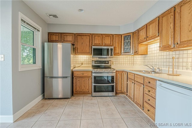 kitchen featuring tasteful backsplash, sink, light tile patterned flooring, and appliances with stainless steel finishes