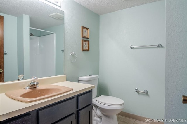 bathroom with vanity, tile patterned flooring, toilet, a textured ceiling, and walk in shower