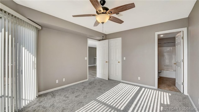 unfurnished bedroom featuring ceiling fan, light colored carpet, and ensuite bath