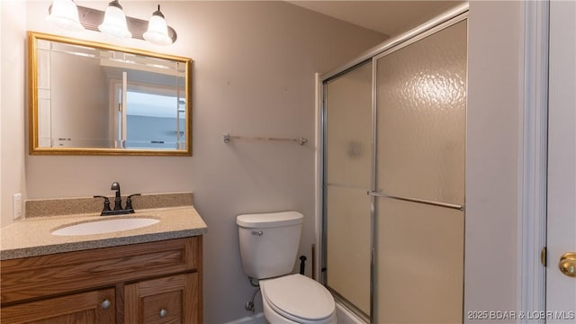 bathroom featuring vanity, toilet, and a shower with shower door