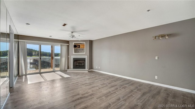 unfurnished living room with hardwood / wood-style floors, ceiling fan, and a water view