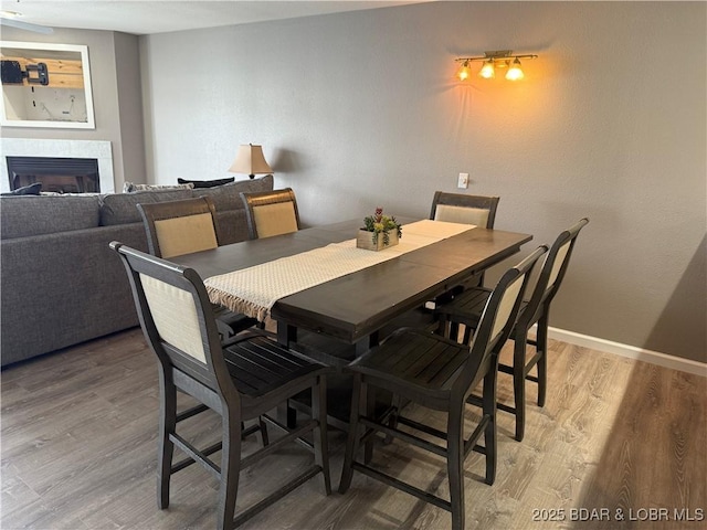 dining area featuring wood-type flooring and a tile fireplace