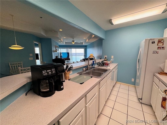 kitchen featuring white refrigerator, sink, ceiling fan, decorative light fixtures, and white cabinetry