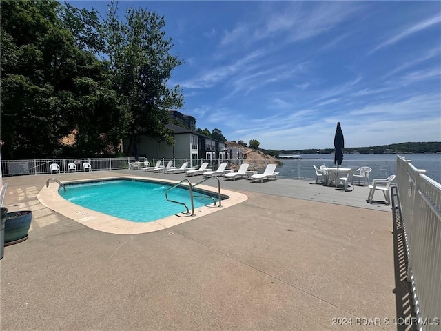 view of pool with a water view and a patio