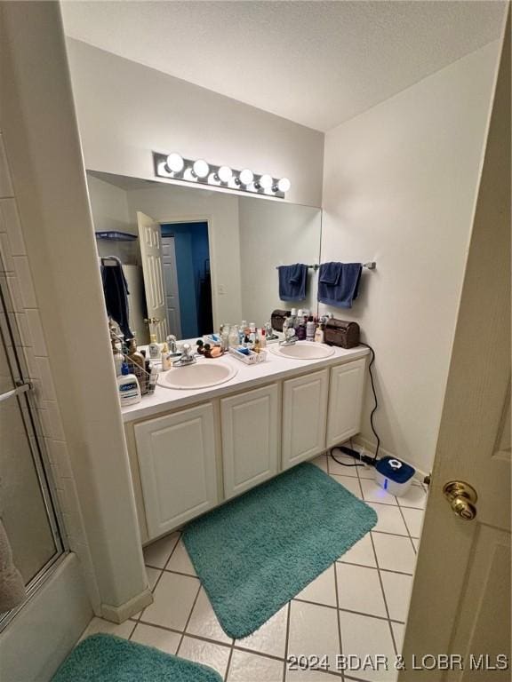 bathroom with tile patterned flooring, vanity, and bath / shower combo with glass door