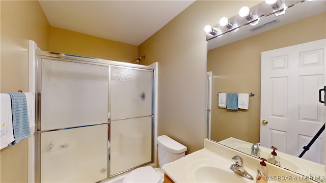 bathroom featuring vanity, toilet, and an enclosed shower