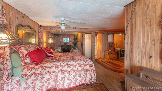 bedroom featuring ceiling fan and wooden walls