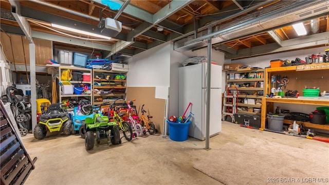 basement with a workshop area and white refrigerator