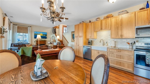 kitchen featuring backsplash, an inviting chandelier, sink, light brown cabinetry, and stainless steel appliances