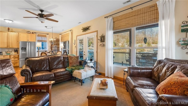 living room featuring ceiling fan with notable chandelier and french doors